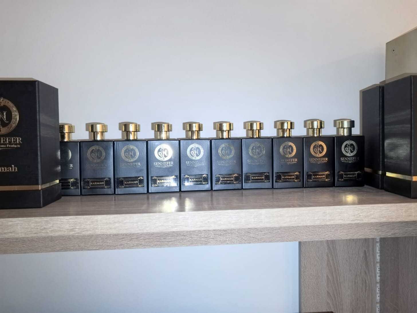 A close row of SENNEFER Karmah extrait bottles with gold caps catching the light